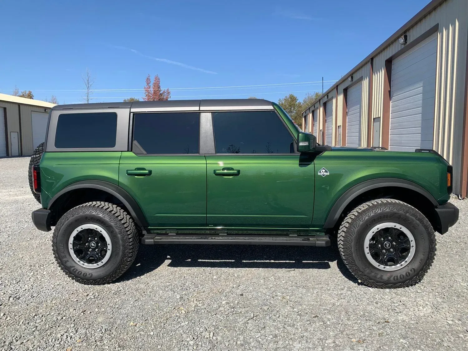 Green Ford Bronco SUV parked outside, against storage units.