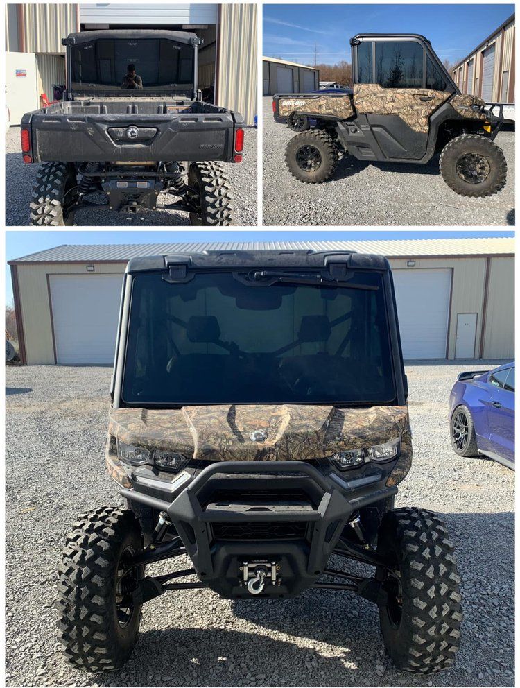 Black and camo UTV with a cab, large tires, outdoors.