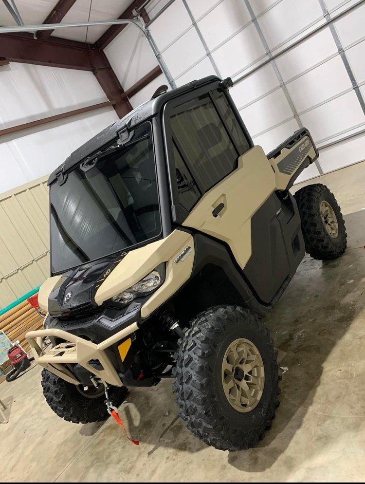 Tan and black UTV with large tires, parked indoors, angled shot.