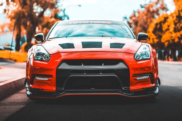 Red Nissan GT-R sports car parked on a road, front view, black accents.