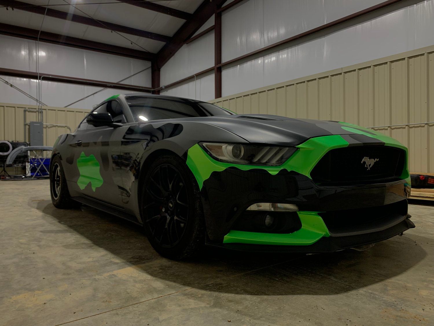 Black and green Ford Mustang in a garage.