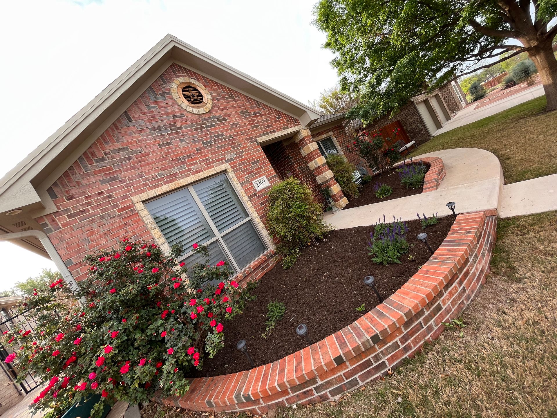Red brick house with curved brick flower bed and walkway.