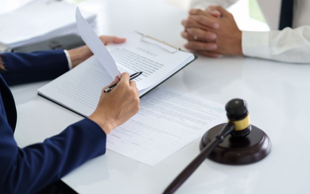 A woman is signing a document next to a judge 's gavel.