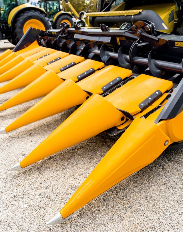 Yellow corn header with pointed snouts on a farm machine, shown close up