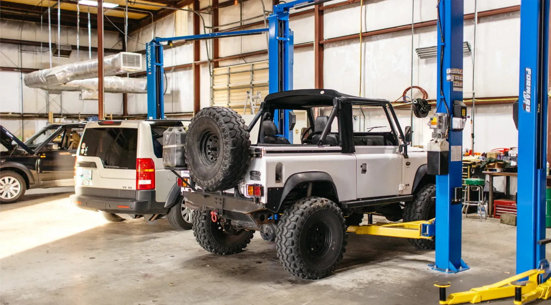 A jeep is sitting on a lift in a garage.
