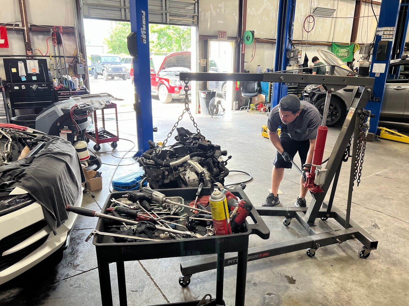Ford truck front end removed in an auto repair shop, with a mechanic standing beside it in New Hanover County, NC