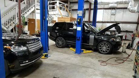 A black range rover is sitting on a lift in a garage.
