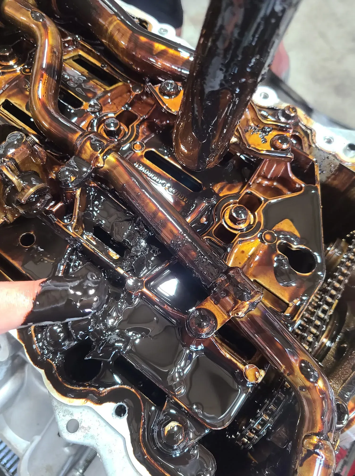A person is cleaning a very dirty engine with a brush.