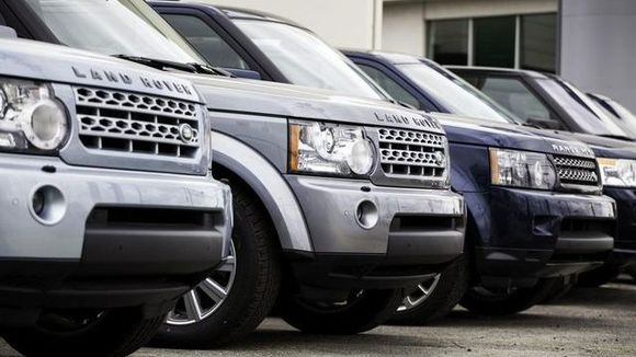 A row of land rovers are parked next to each other in a parking lot.