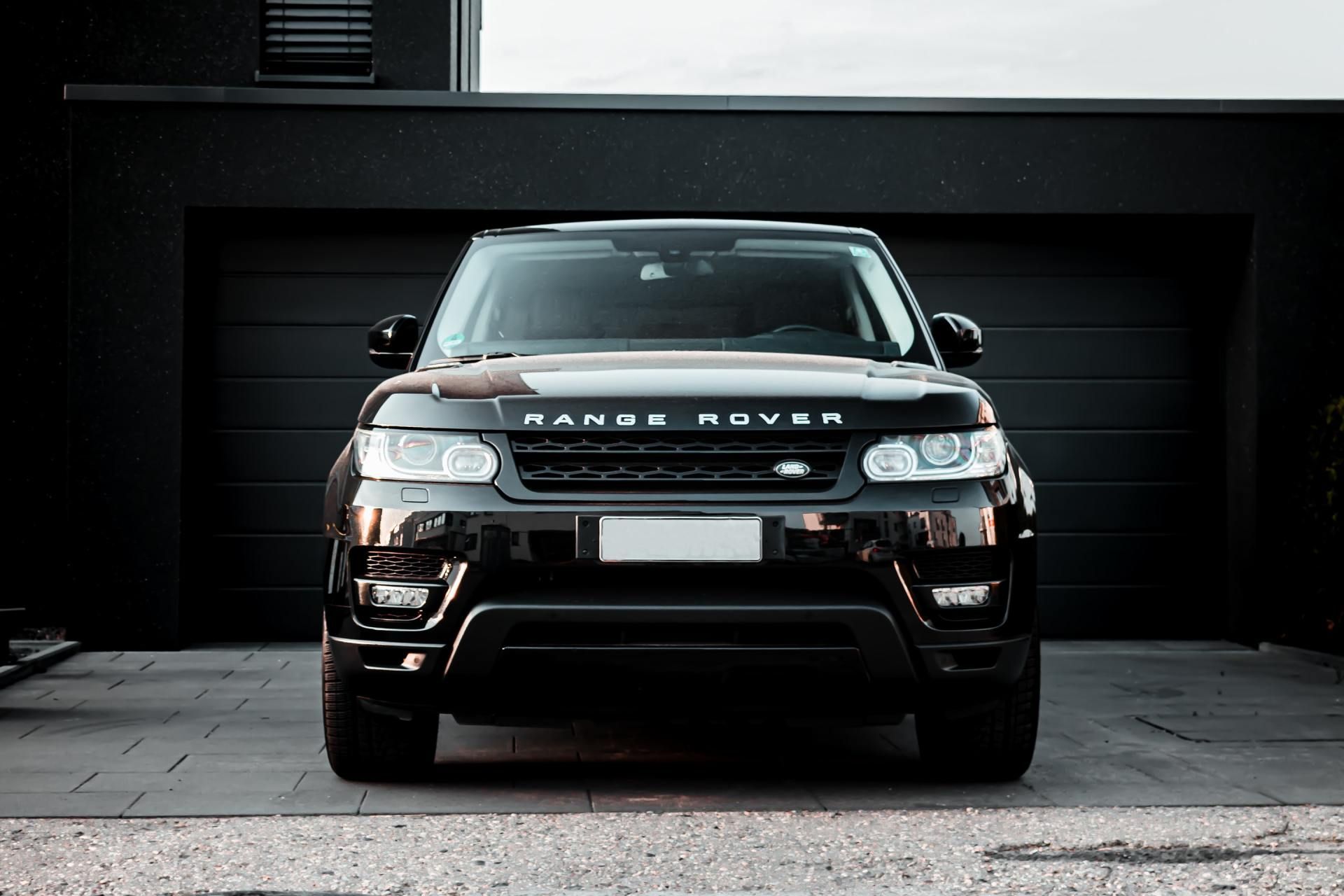 A black range rover is parked in front of a black garage door.