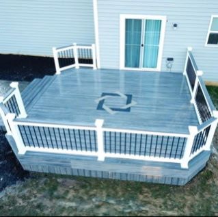 Blue wooden deck with white railing and double doors on a house patio.