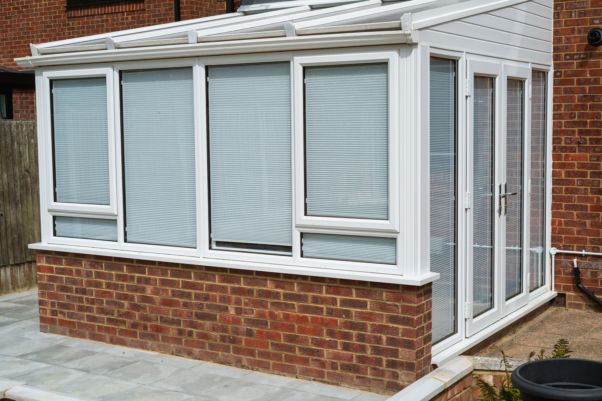 Brick sunroom extension with white-framed windows and glass doors attached to a house