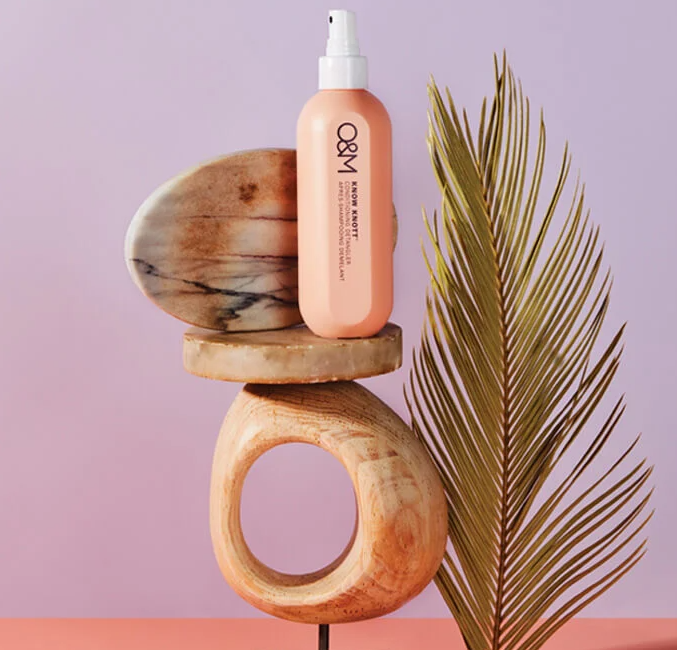 Une bouteille de produit capillaire en équilibre sur des formes en bois,