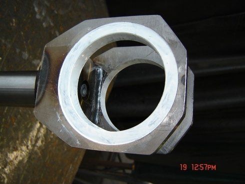 Vista ravvicinata di un componente meccanico metallico con un rivestimento interno circolare in plastica bianca saldato all'interno di una struttura ottagonale.