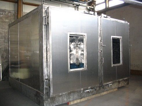 Ampia camera industriale in acciaio inox con due porte e finestre di osservazione rettangolari, situata in un ambiente di magazzino.