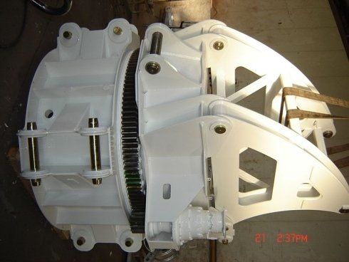 Un robusto meccanismo girevole industriale di colore bianco, dotato di ingranaggio circolare e strutture di supporto in metallo rinforzato.