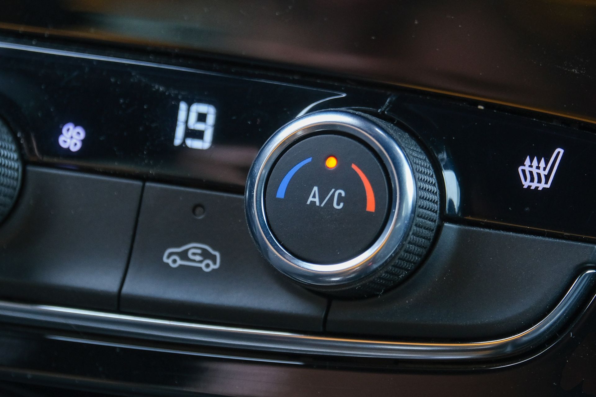 Car dashboard climate controls showing 19°C, A/C dial, rear defrost, and seat heater icons