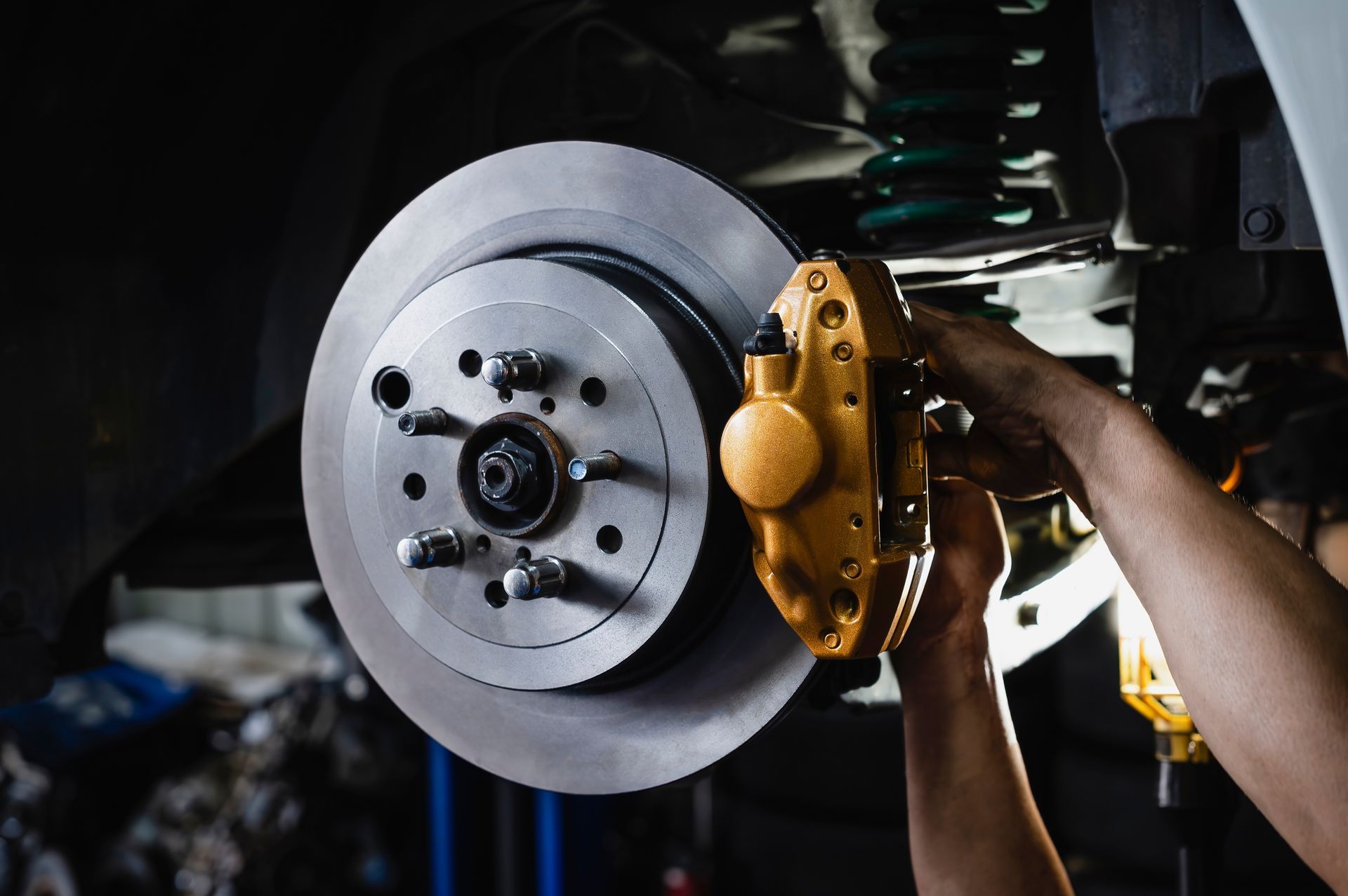 Close-up of a car brake rotor being serviced with a gold brake caliper