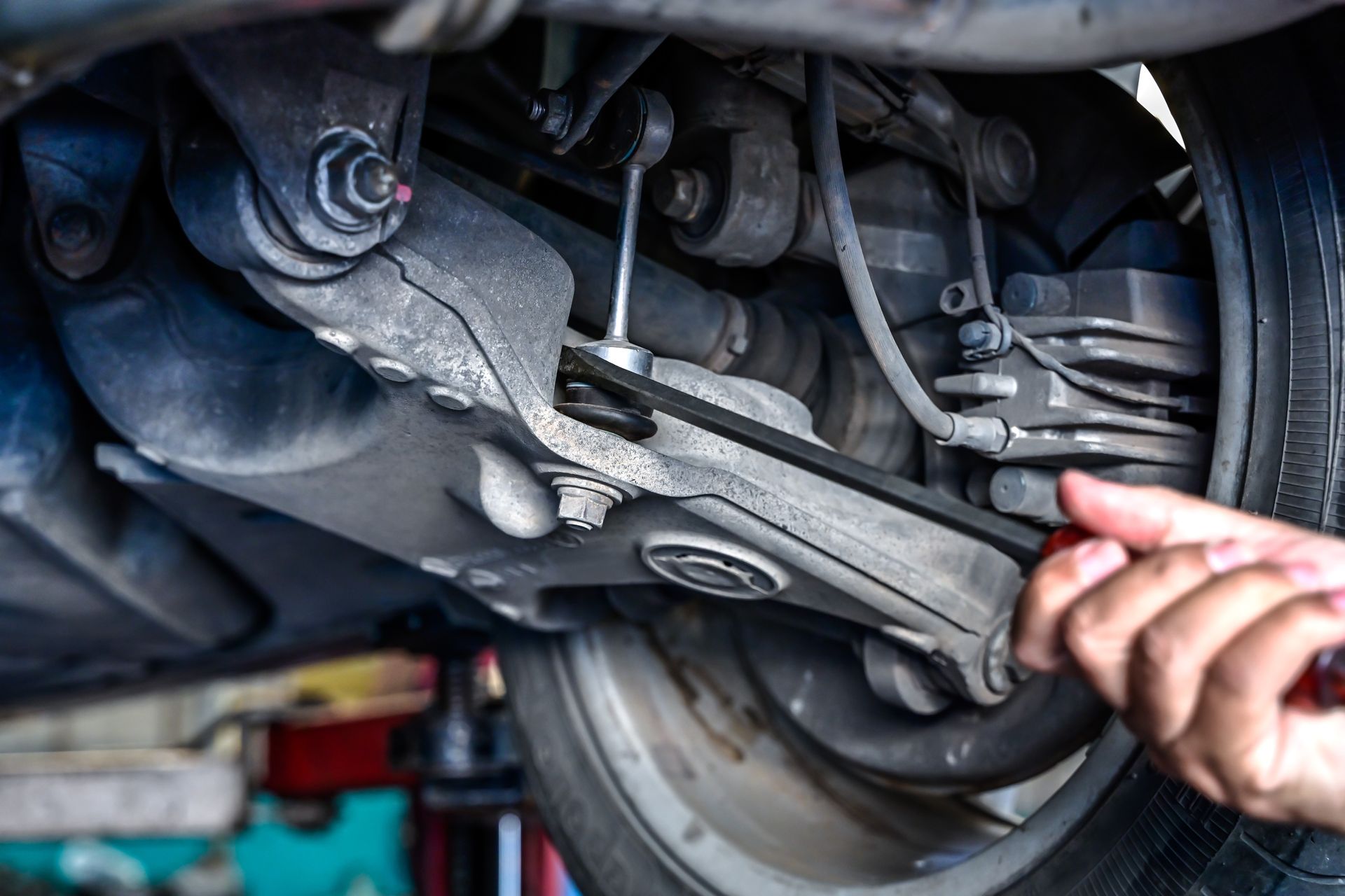 Mechanic using a wrench to inspect a car’s suspension under the wheel well