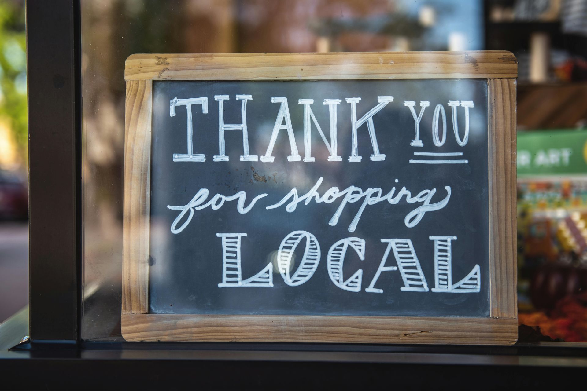 A blackboard with the words `` thank you for shopping local '' written on it.