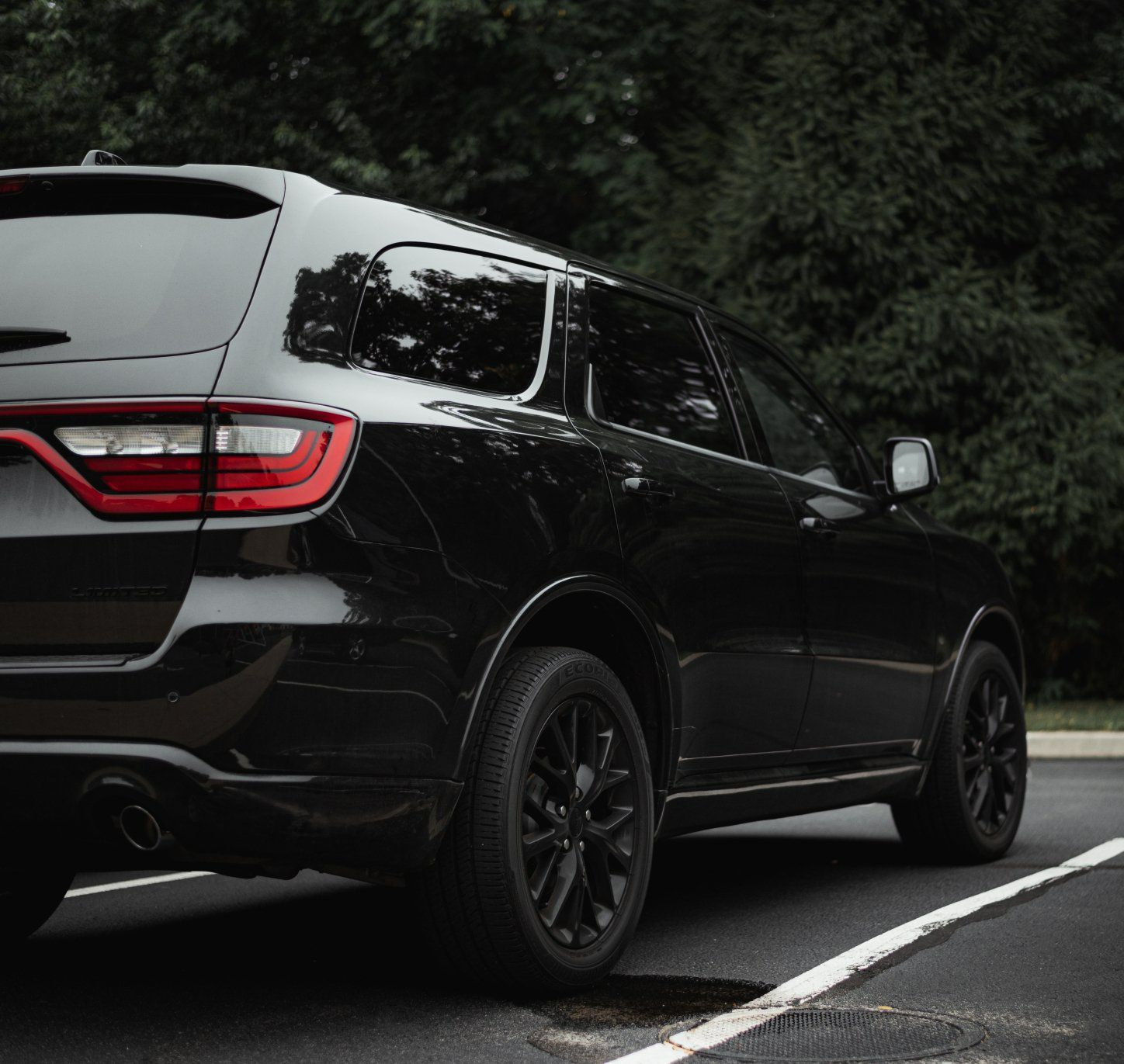 Black SUV parked next to a line, trees in the background.