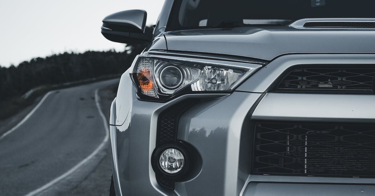 Silver Toyota 4Runner SUV, partially visible on a winding road, front headlight detail.