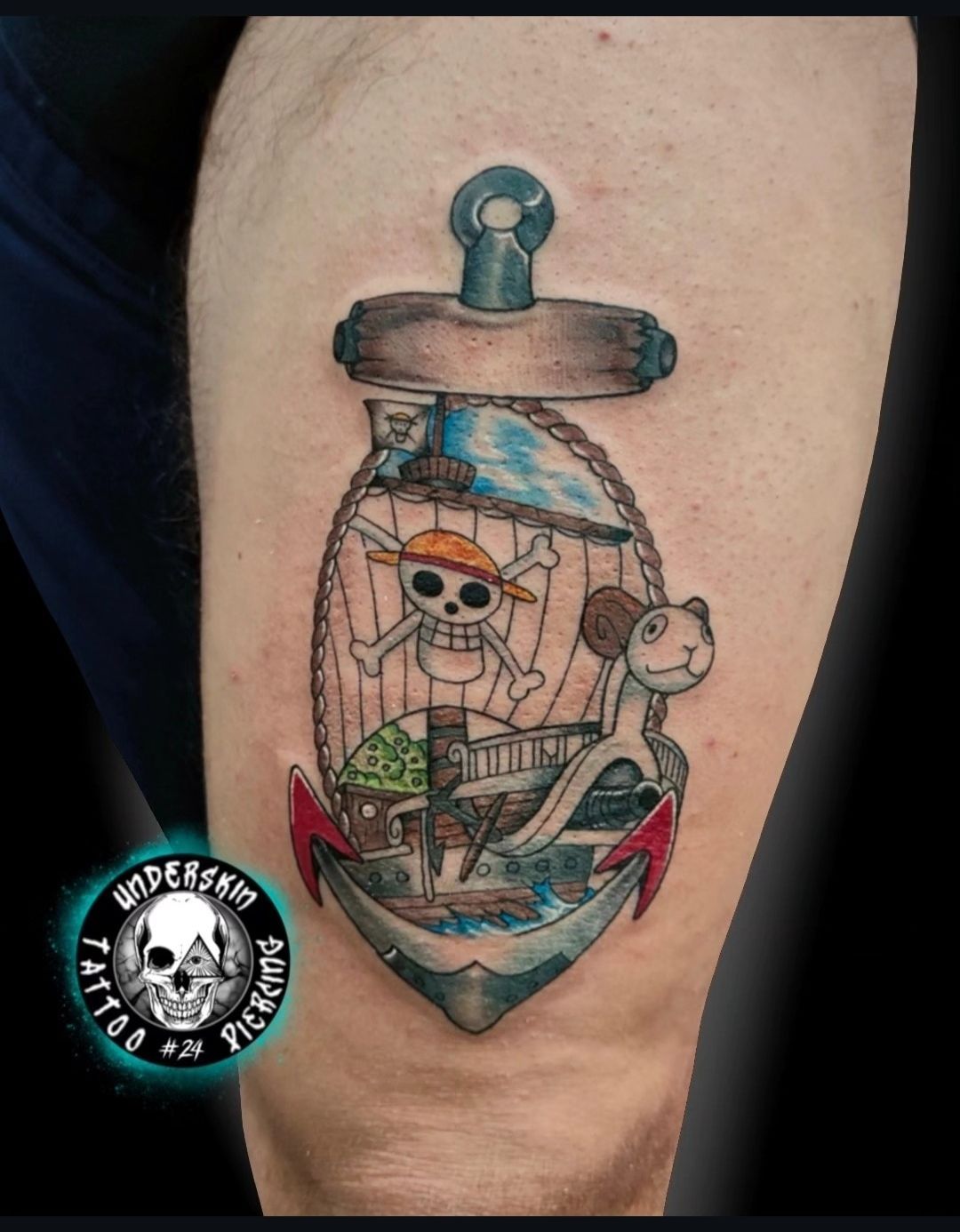 Tatuaggio a colori di one piece un pirata con un teschio in una bottiglia con acqua blu e una piccola scimmia sul braccio