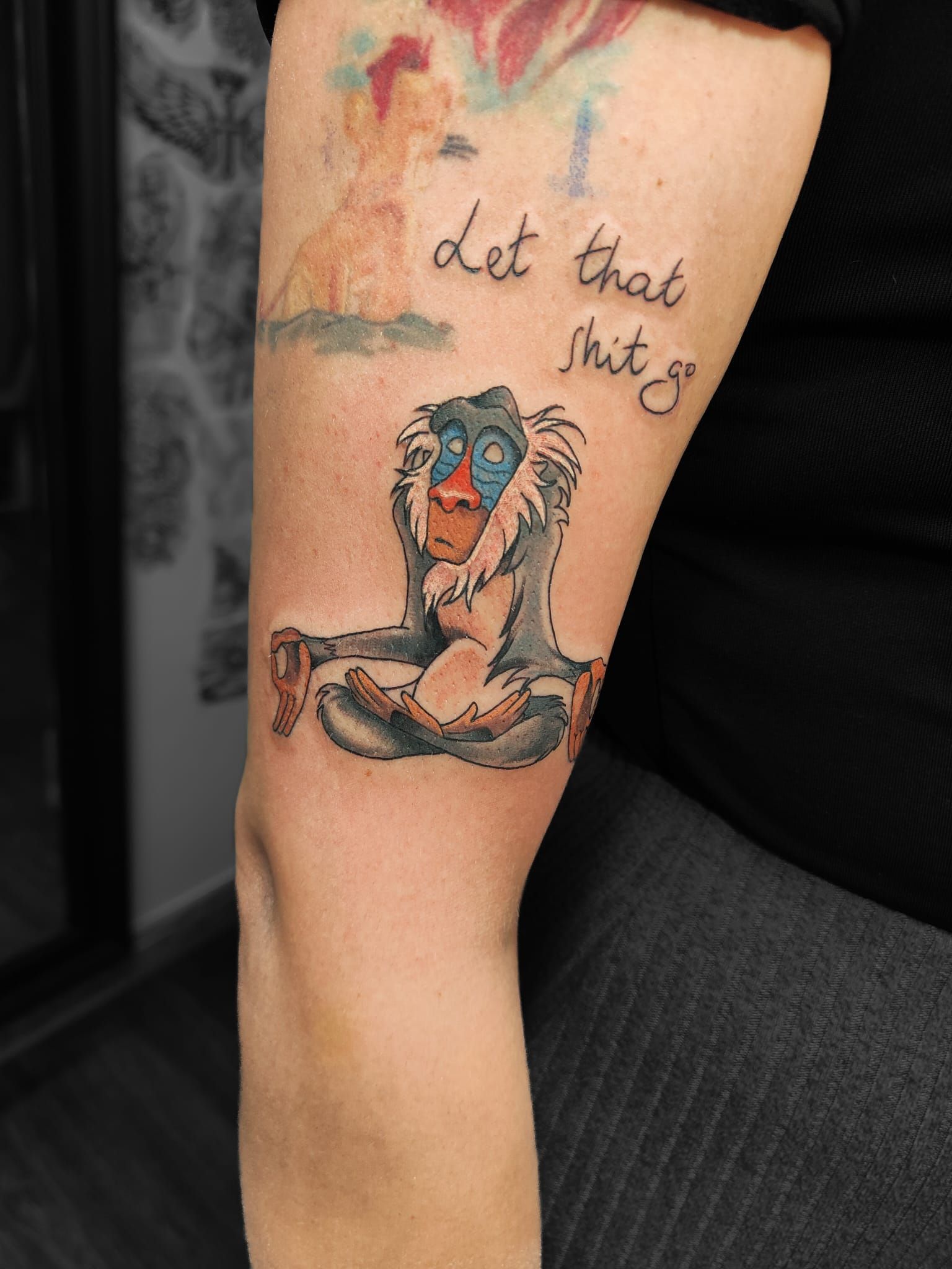 Primo piano di un tatuaggio sulla gamba con un leone e rafiki la scritta