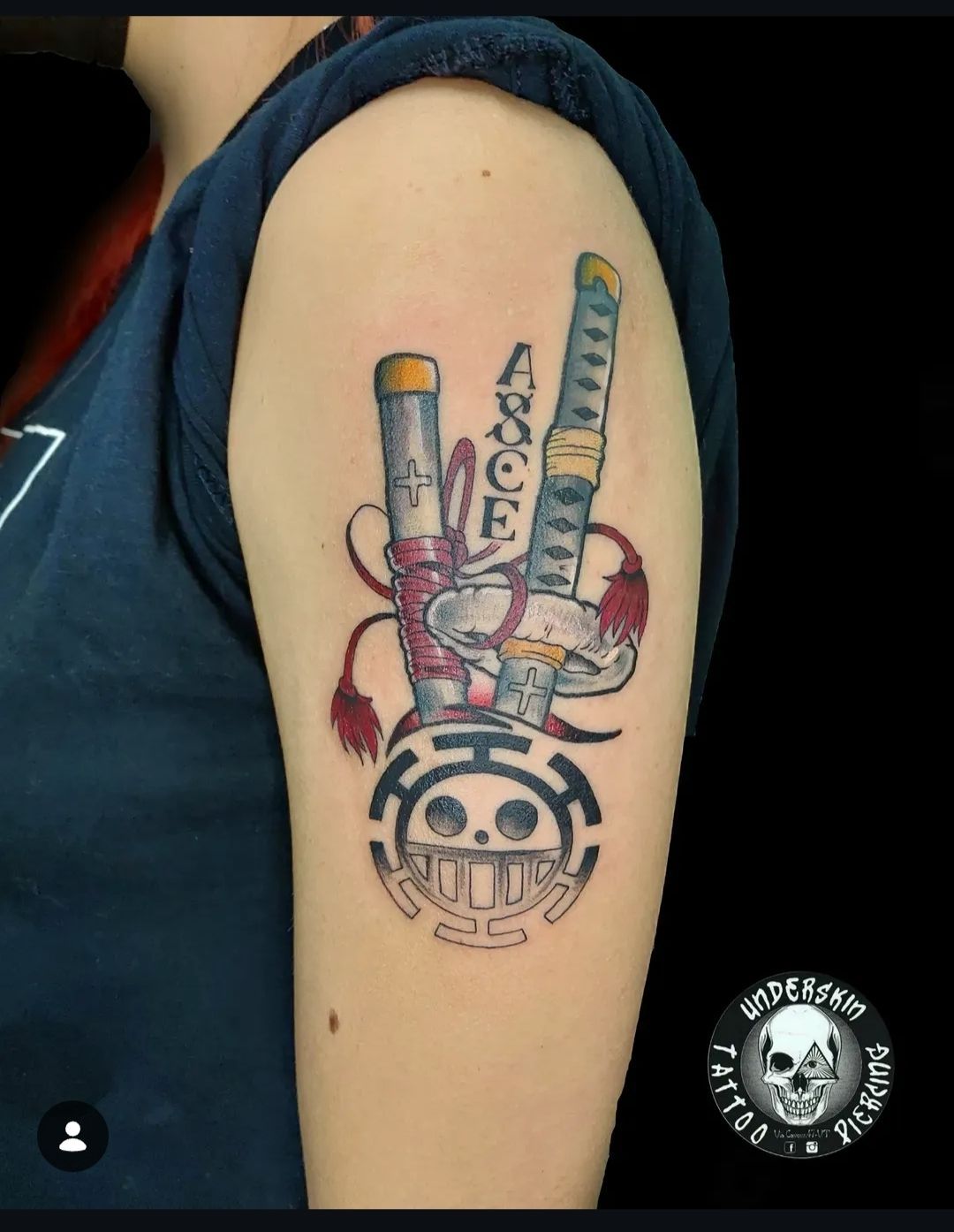 Tatuaggio sul braccio raffigurante una mano stilizzata che fa il segno della pace, con dettagli colorati e scritte verticali.