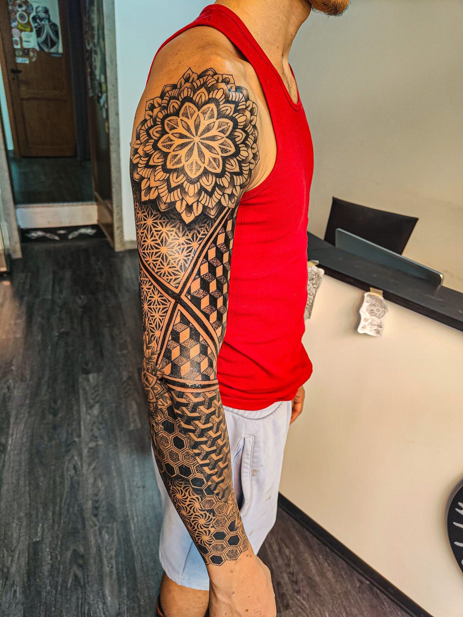Vista laterale di una persona che mostra un braccio completamente tatuato di nero.