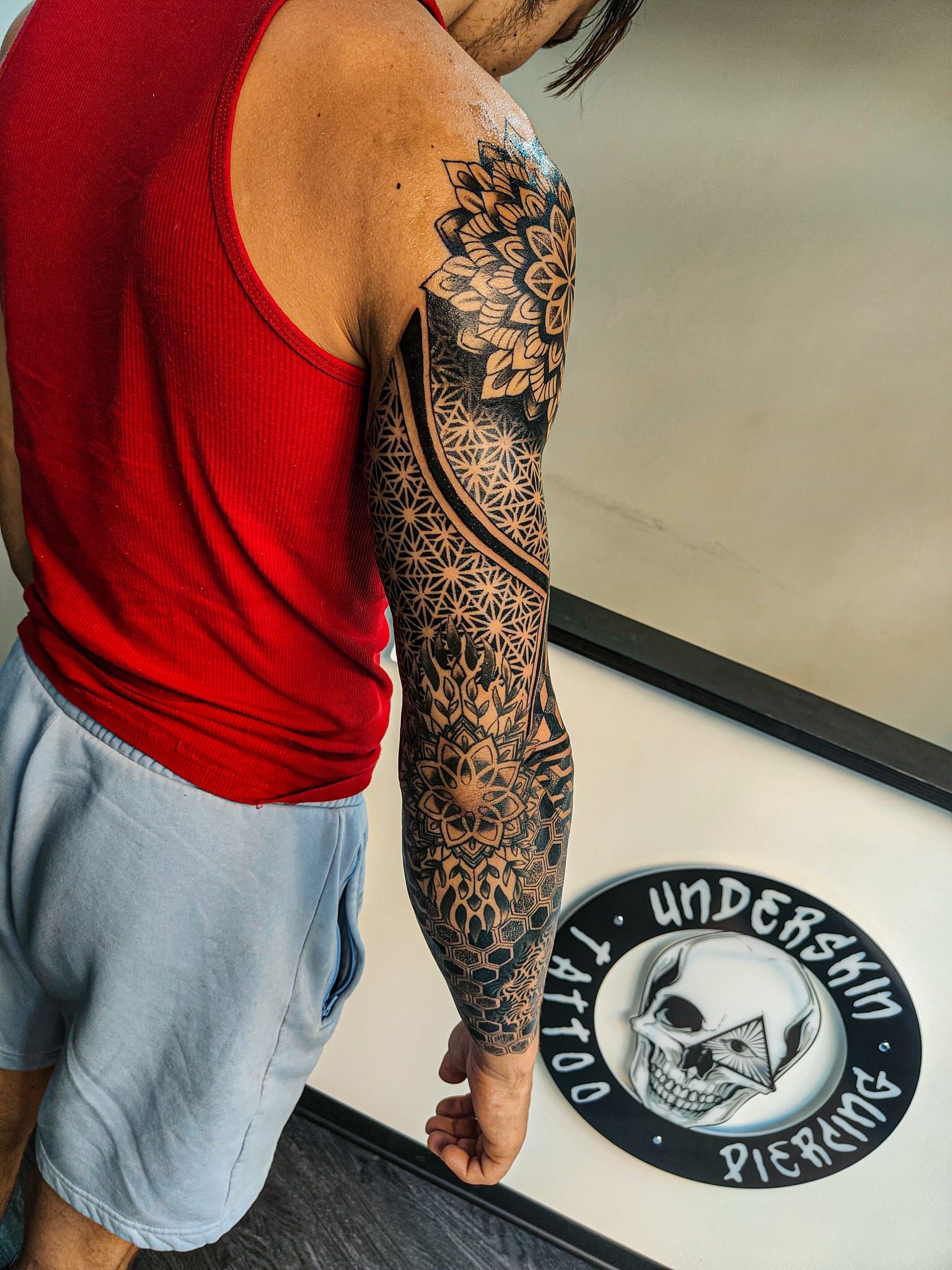 Una persona con un braccio tatuato geometrico nero