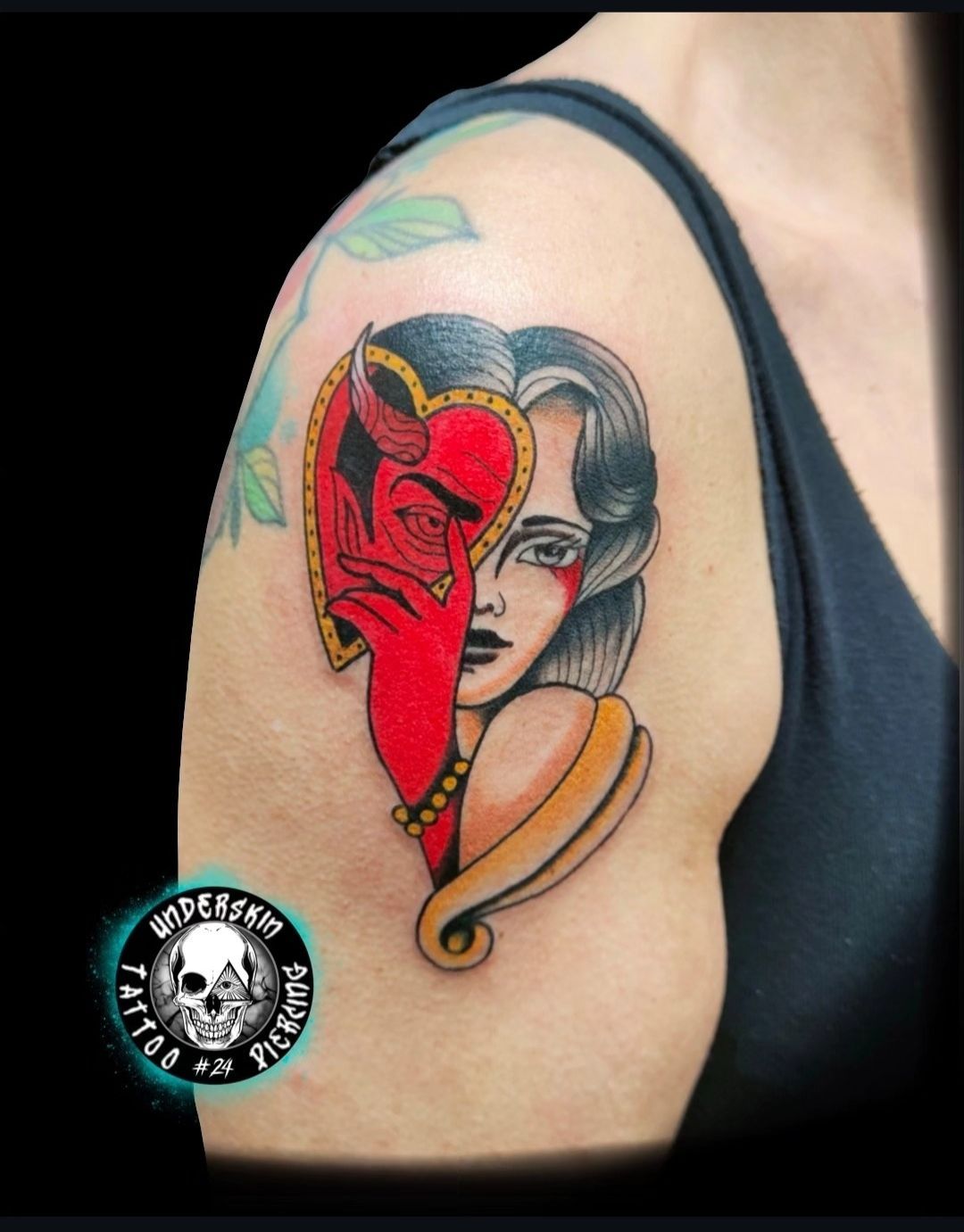 Tatuaggio a mezza maschera colorato in rosso, nero e beige sulla parte superiore del braccio.