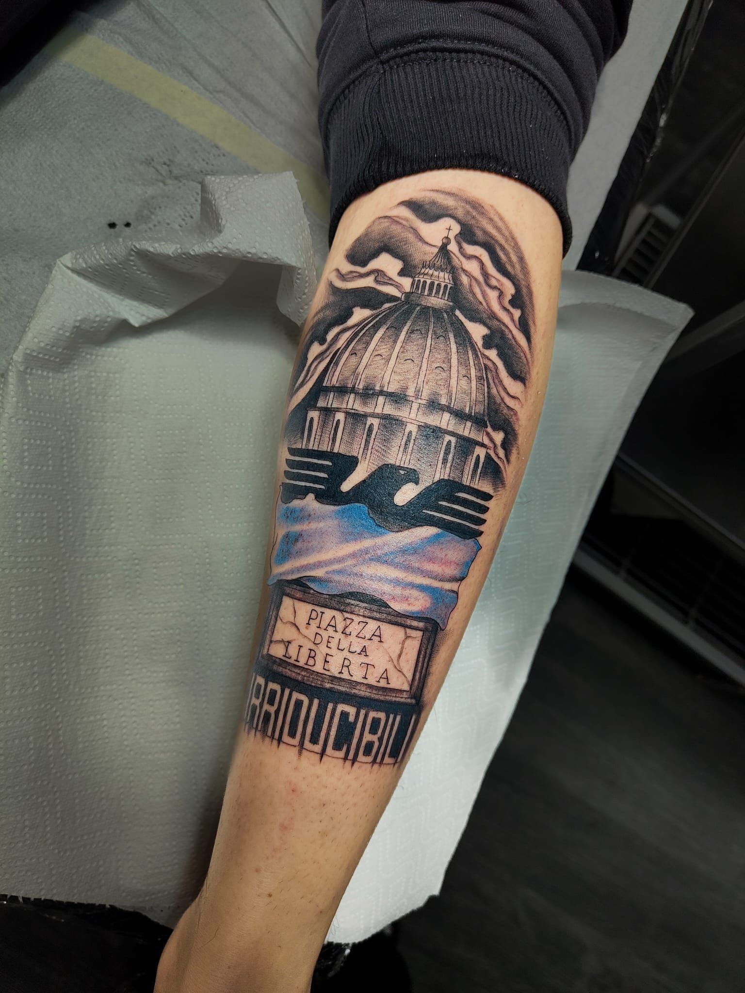 Avambraccio con un tatuaggio colorato raffigurante una montagna, la luna e un tramonto.