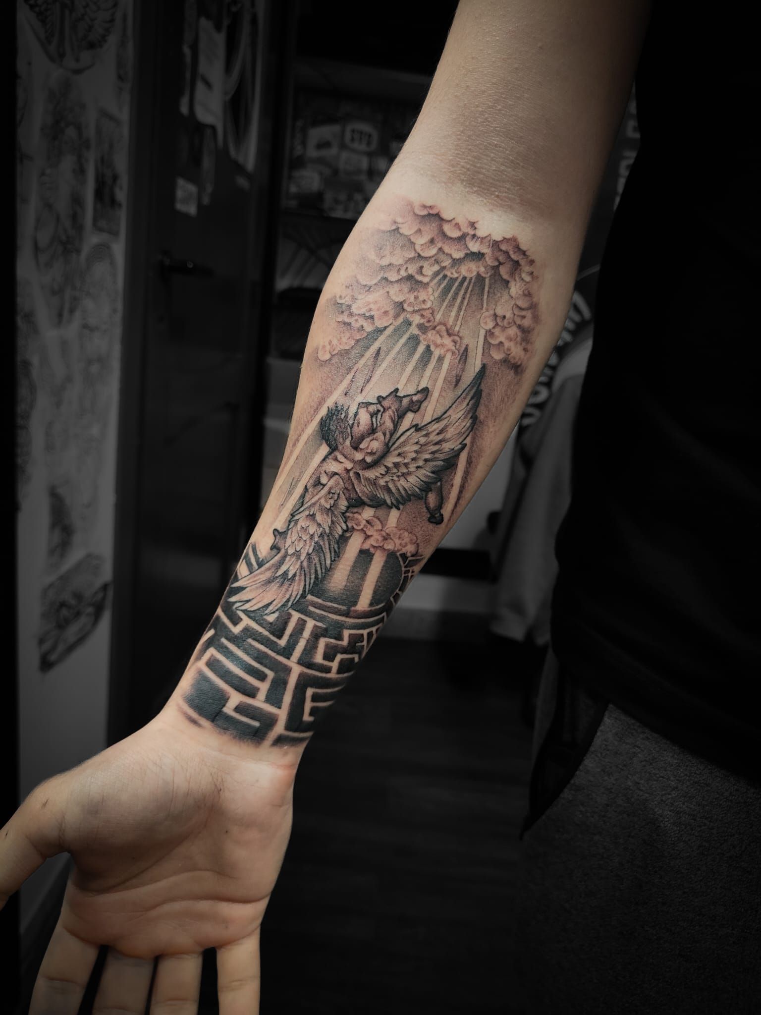 Primo piano di un tatuaggio a manica sull'avambraccio, raffigurante un volto e motivi geometrici, sul braccio di una persona.