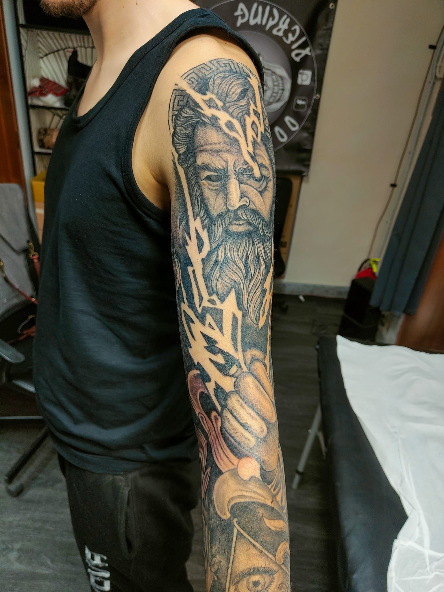 Una persona in piedi con il braccio completamente ricoperto da un elaborato tatuaggio a manica in bianco e nero.