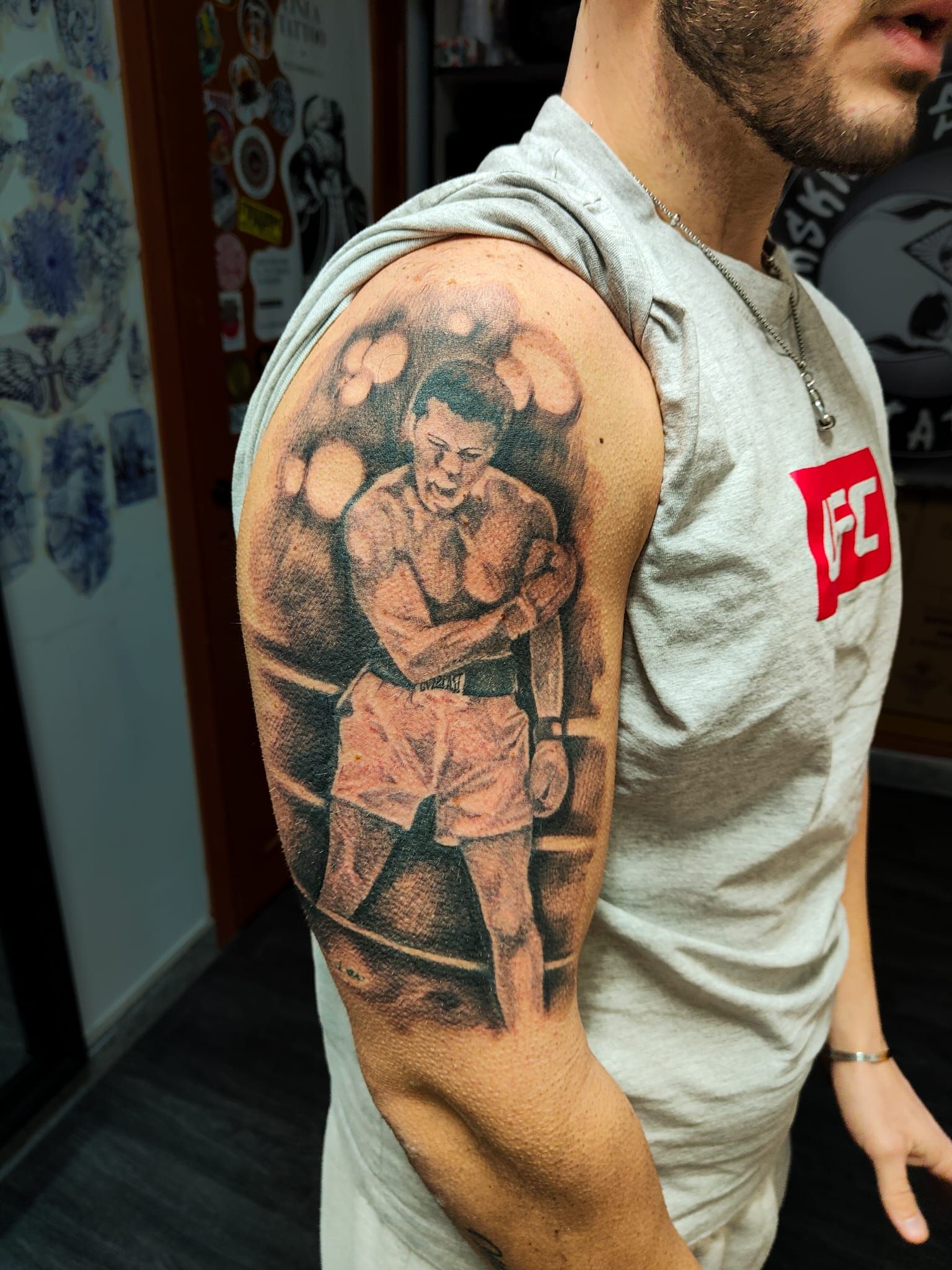 Primo piano di un braccio con un grande tatuaggio in bianco e nero sulla parte superiore, indossato con una maglietta.