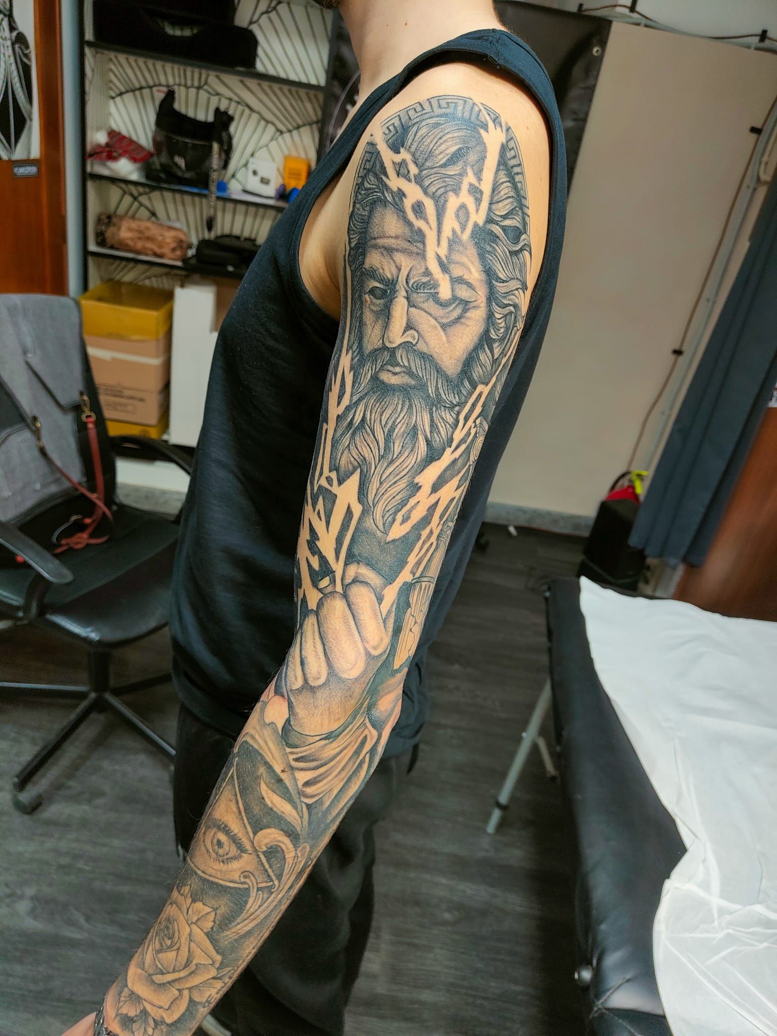 Il braccio presenta un realistico tatuaggio in bianco e nero raffigurante una uomo barbuto circondata da fulmini