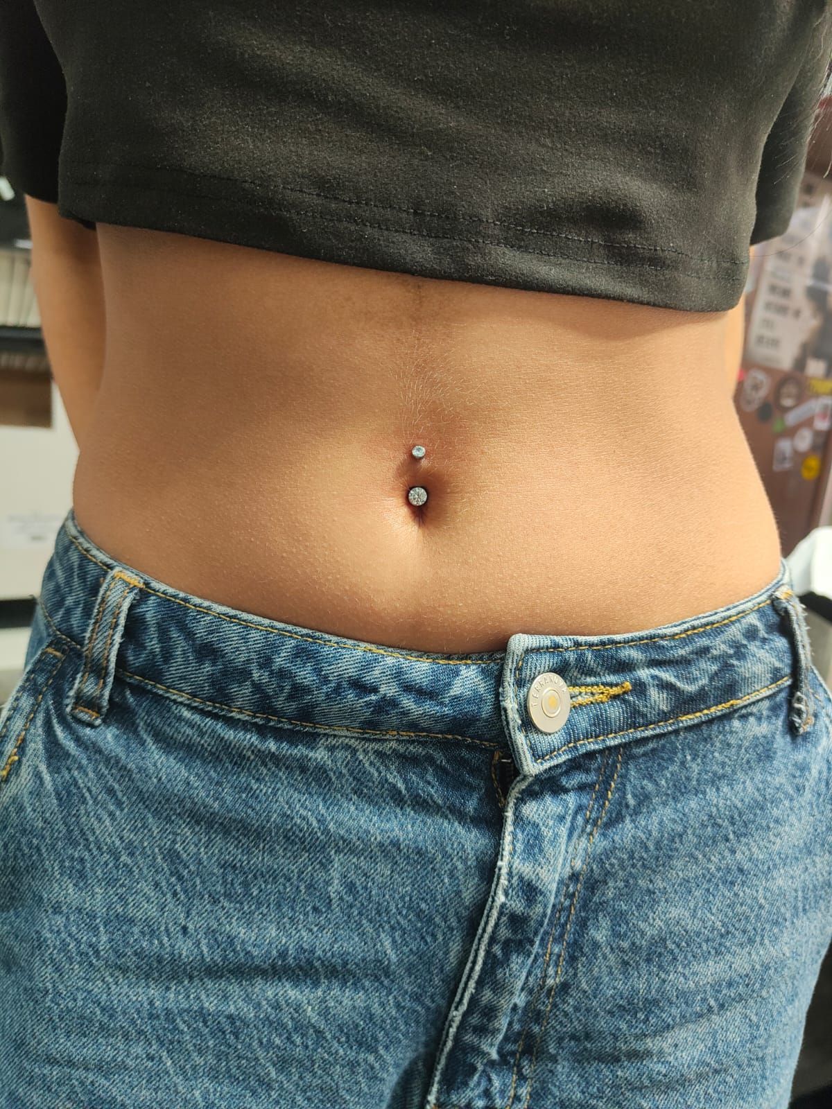 Pantaloncini corti in maglietta verde e jeans blu con piercing all'ombelico