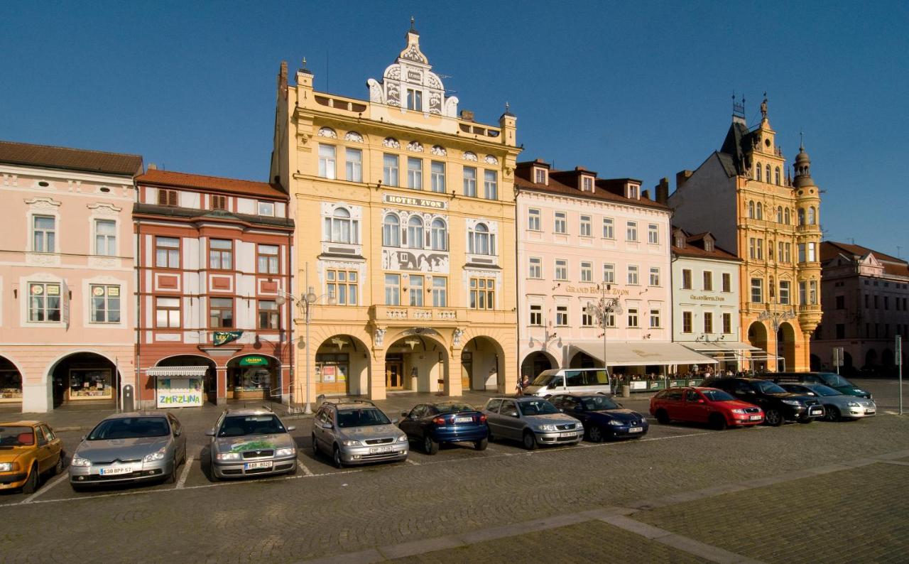 Před budovou parkuje řada aut.
