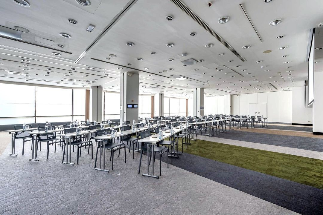 Velká konferenční místnost s řadami černých židlí