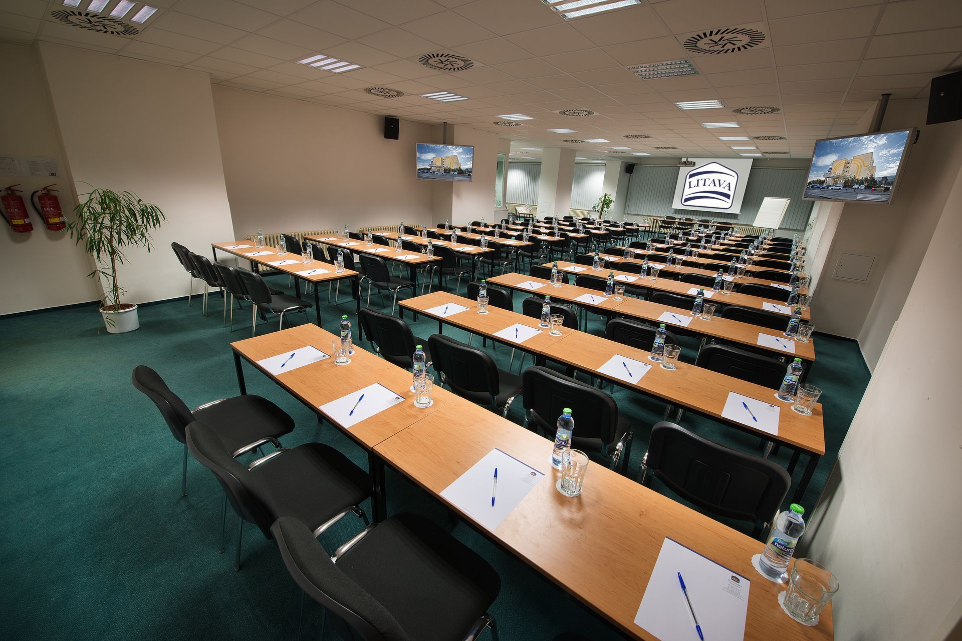 Velká konferenční místnost se stoly a židlemi připravenými pro jednání