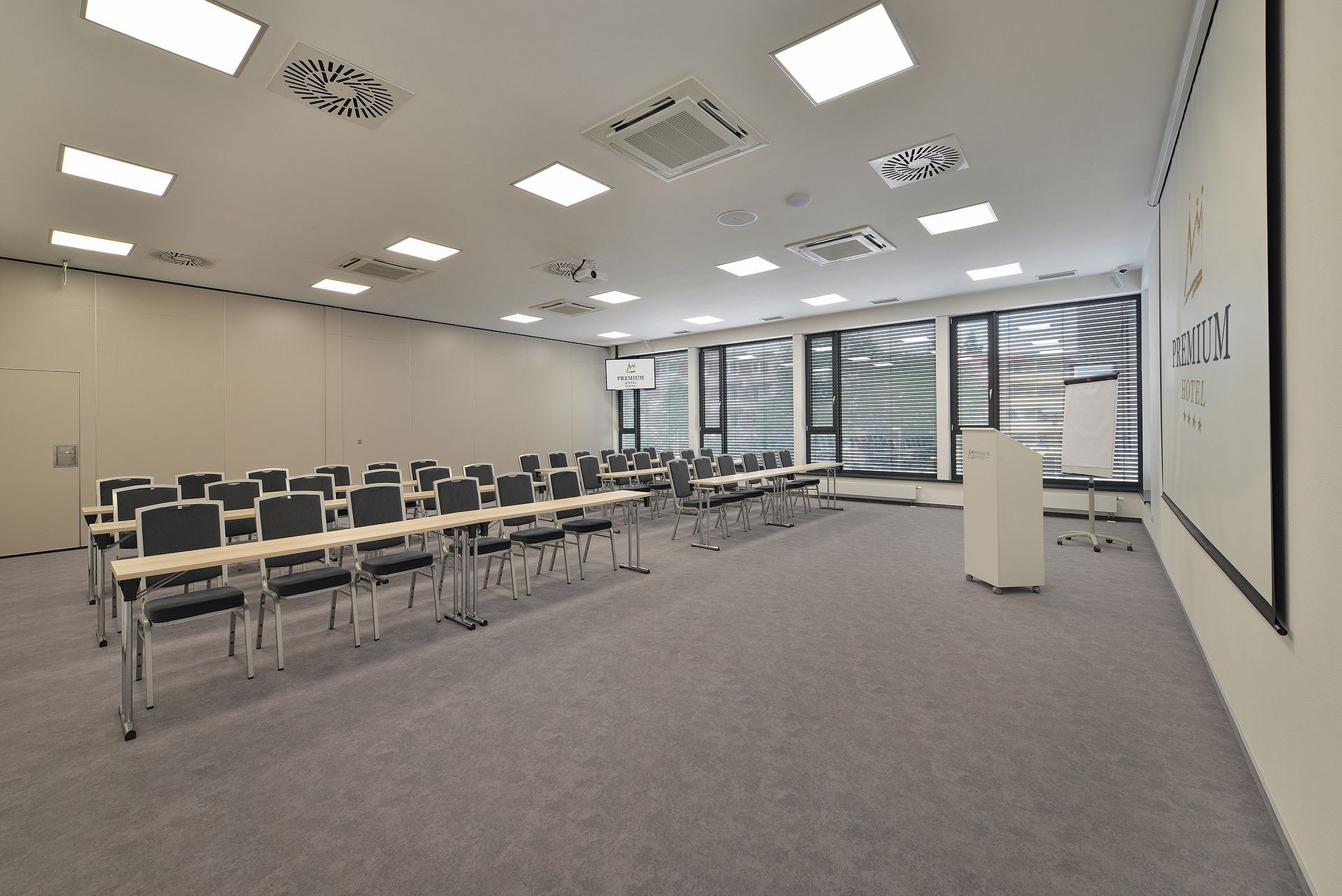 Prázdnou konferenční místnost se stoly a židlemi a pódiem
