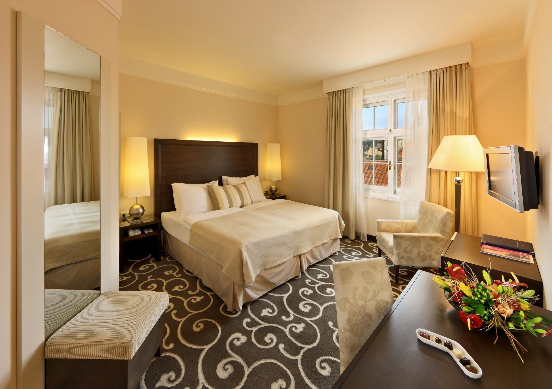 Hotelový pokoj s manželskou postelí , židlí , stolem a televizí.