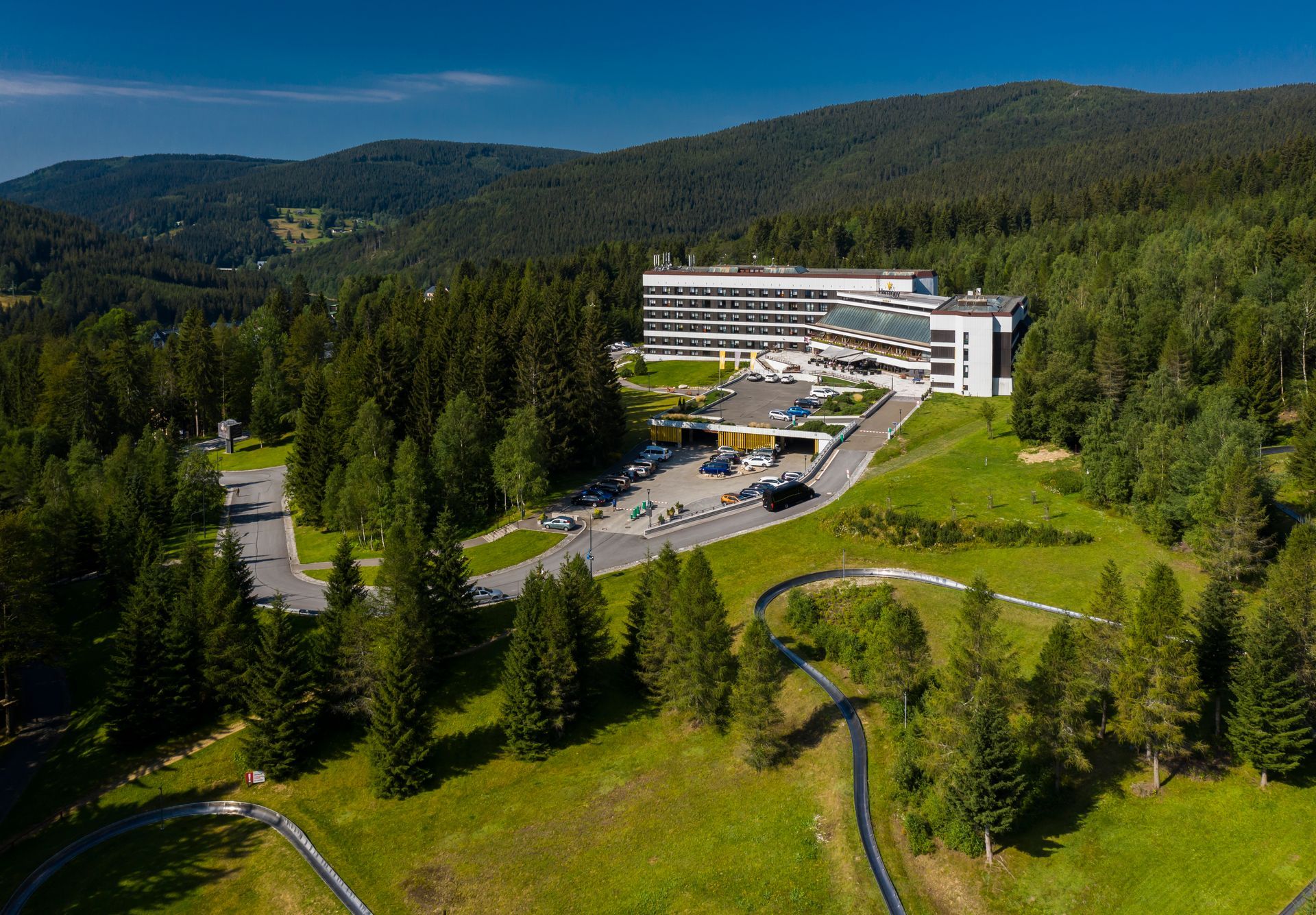 Letecký pohled na hotel obklopený stromy a horami.
