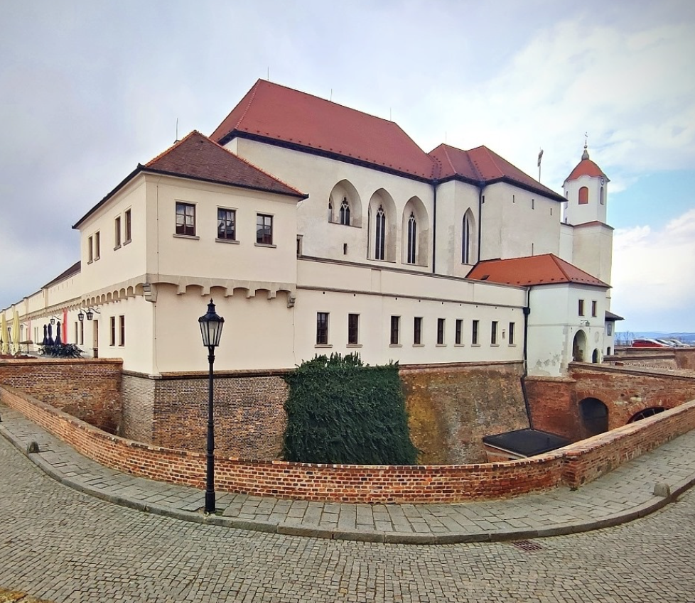 Velká bílá budova s ​​červenou střechou a cihlovou zdí