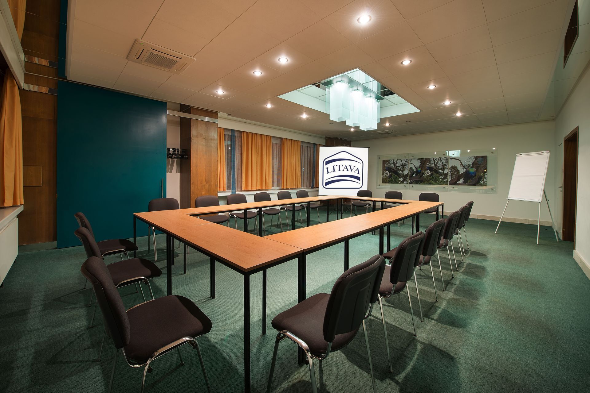 Konferenční místnost se stoly a židlemi a promítacím plátnem