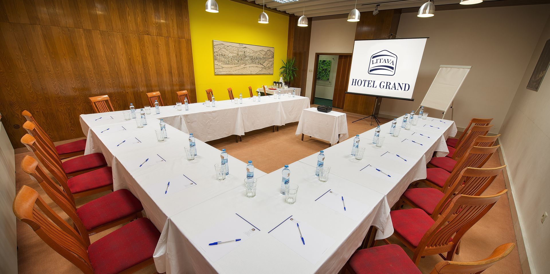 Konferenční místnost se stoly a židlemi připravenými pro jednání