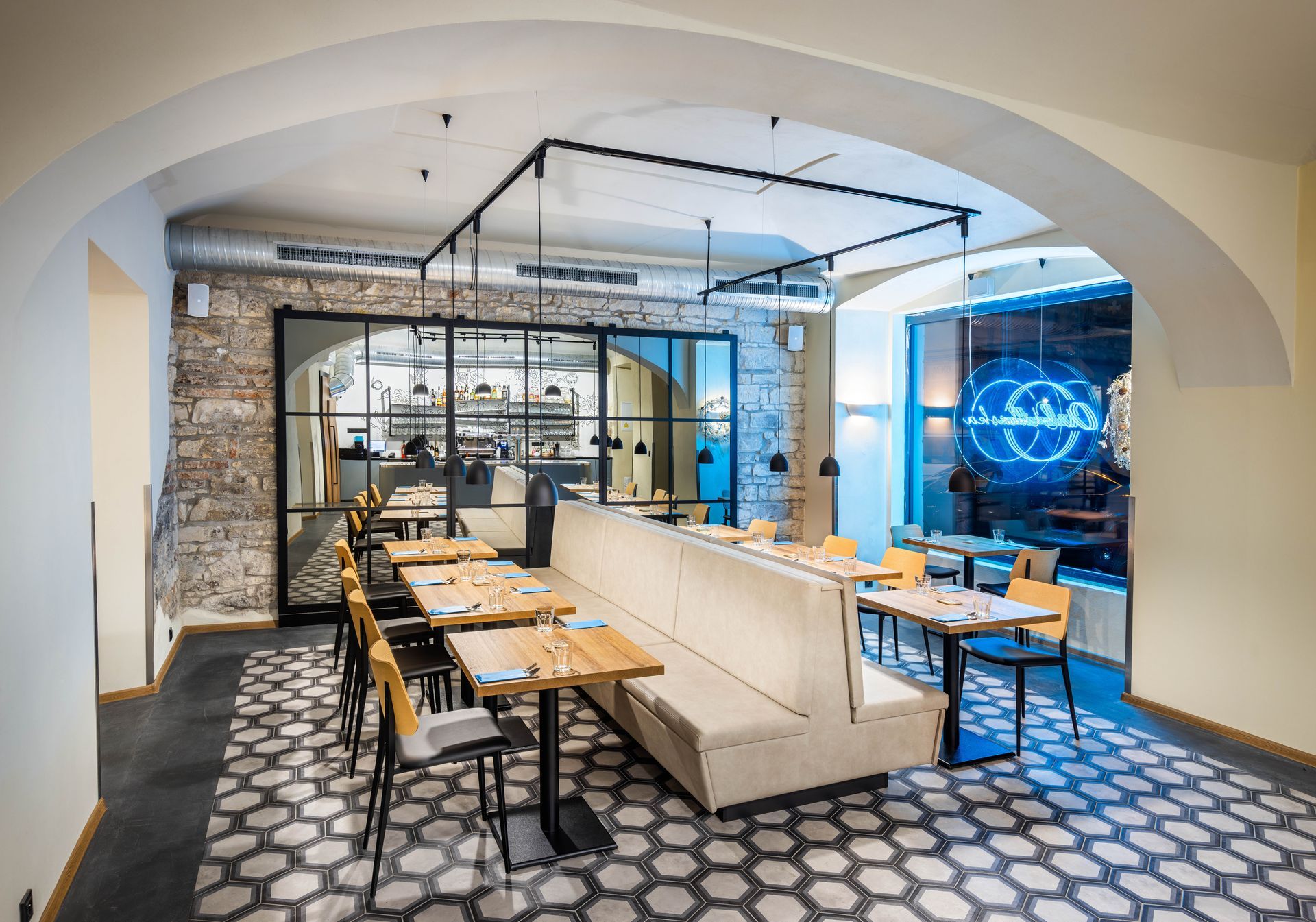 Restaurace se stoly a židlemi a gaučem uprostřed místnosti.