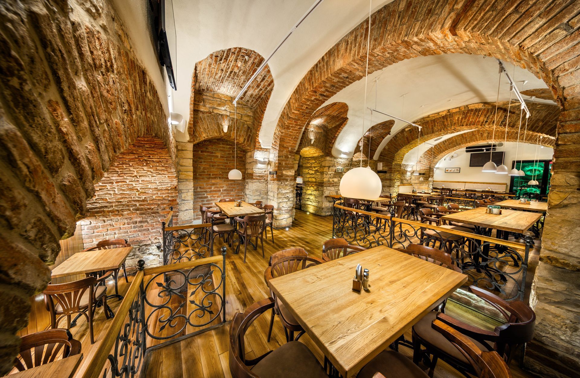 Restaurace s dřevěnými stoly a židlemi ve zděné budově.