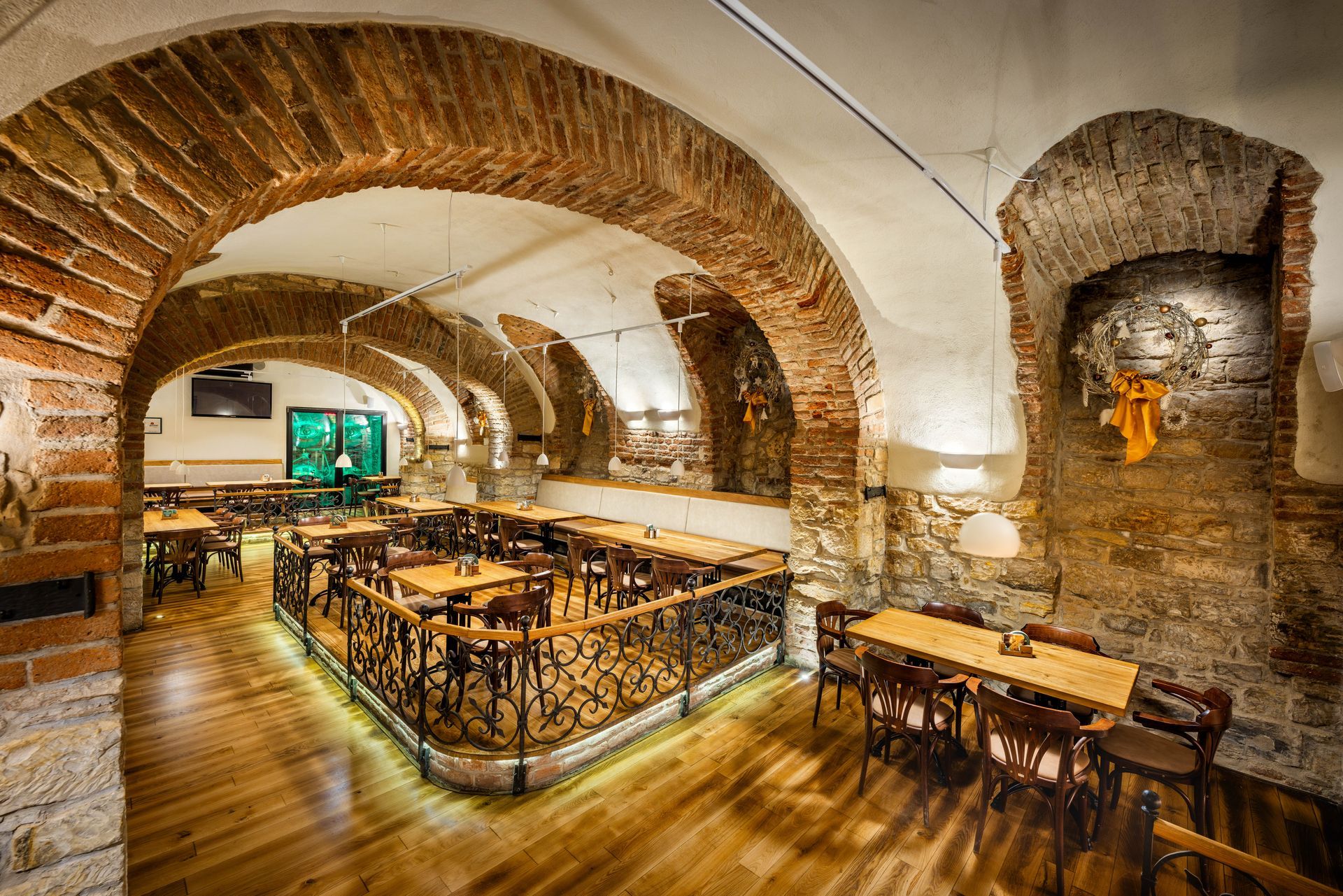 Restaurace s dřevěnými stoly a židlemi a cihlovými zdmi.